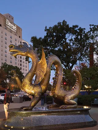 a dramatically lit dragon statue with a Drexel University sign in the background