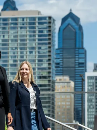 Three LeBow businesswomen standing together with Philadelphia's skyline behind them
